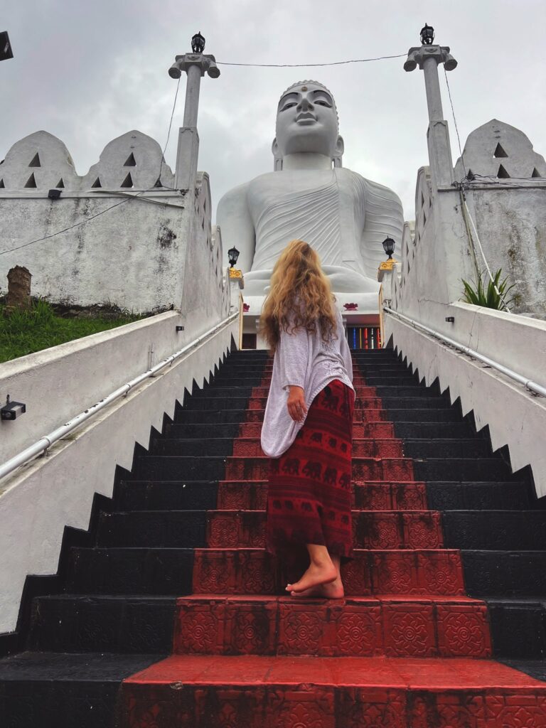 Frau stehr auf einer Treppe und blickt in Richtung eines Tempels.